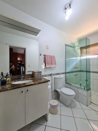 Foto de um banheiro interno com revestimento cerâmico e box de vidro.