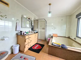 Foto de um banheiro com revestimento cerâmico e bancada de madeira.