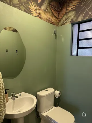 Banheiro com pia e vaso sanitário em parede verde claro.