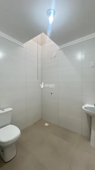 Foto de um banheiro interno com revestimento branco e piso claro.