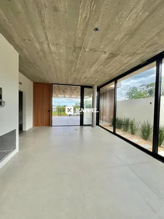 Ambiente amplo com piso de concreto e grandes portas de vidro que dão vista para o exterior.
