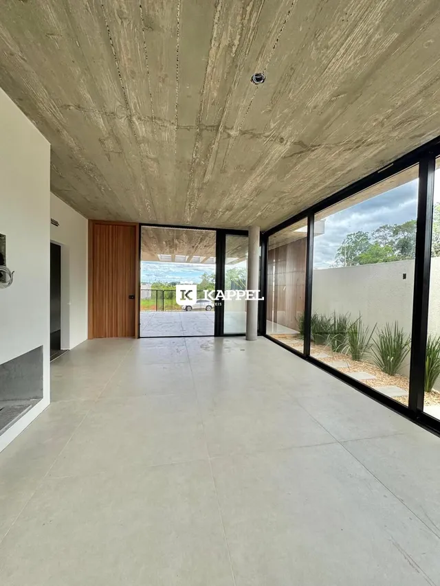 Ambiente amplo com piso de concreto e grandes portas de vidro que dão vista para o exterior.