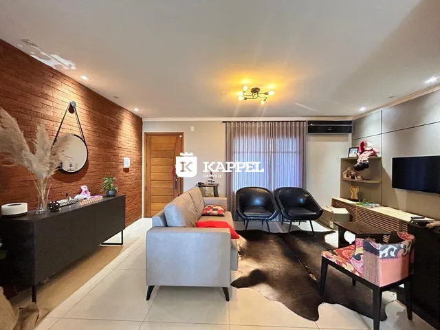 Sala de estar moderna com sofá e poltronas escuras em ambiente bem iluminado.