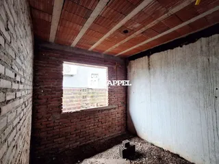 Parede de tijolos expostos com teto de madeira em uma área interna em construção.
