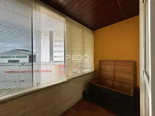 Interior de um cômodo com parede amarela e piso de madeira.