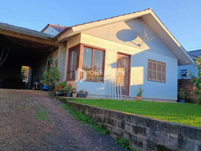 Fachada de uma casa em Lajeado, Brasil, com jardim e estrada de terra em primeiro plano.