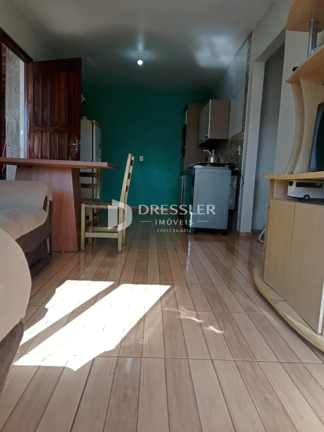 Uma sala de estar com piso de madeira clara e paredes verdes.