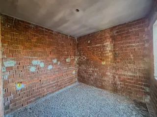 Parede interna de tijolos aparentes com tubulações expostas em uma área residencial.