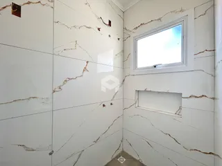 Parede interna com revestimento de mármore branco e uma janela.