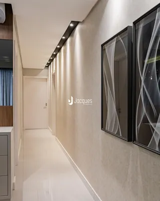 Hall de entrada longo com piso claro e paredes texturizadas.