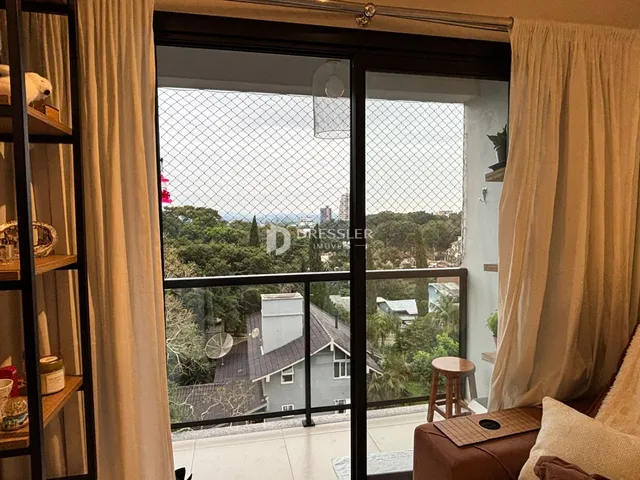 Vista da sala de estar com portas de vidro que dão para uma paisagem verde.