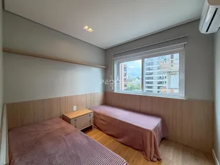 Quarto com cabeceira de madeira e janela com vista da cidade.