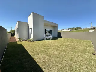 Vista externa de uma casa moderna com jardim gramado.
