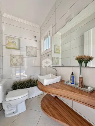 Foto de um banheiro com azulejos brancos e bancada de madeira.