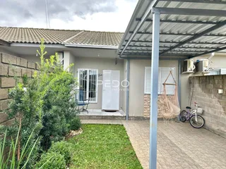 Fachada de uma residência com jardim e área externa coberta.