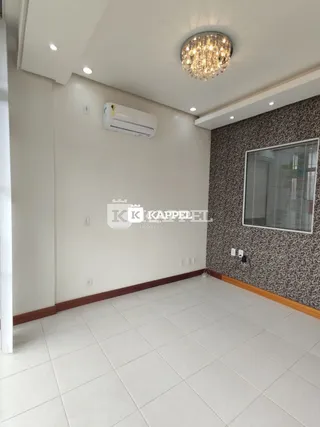 Uma sala de estar com piso de cerâmica branca e parede texturizada cinza.