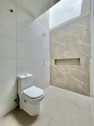 Foto interna de um banheiro moderno com revestimento de mármore claro.