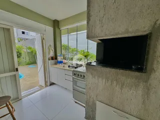Sala de estar e cozinha com vista para o jardim através de portas de vidro.