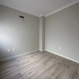 Foto de um cômodo interno com paredes cinzas e piso de madeira.