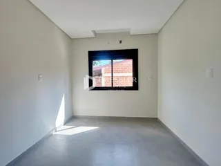 Interior de um espaço com uma grande janela de tijolos à vista.