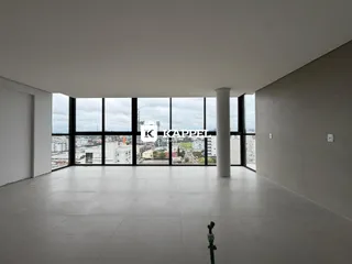 Uma sala ampla com grandes janelas oferece uma vista panorâmica da cidade.