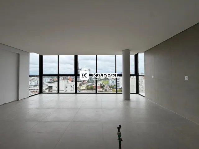 Uma sala ampla com grandes janelas oferece uma vista panorâmica da cidade.