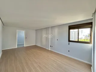 Ambiente interno de uma sala com piso de madeira clara e janela.