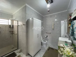 Foto de um banheiro com revestimento cerâmico e armário branco.
