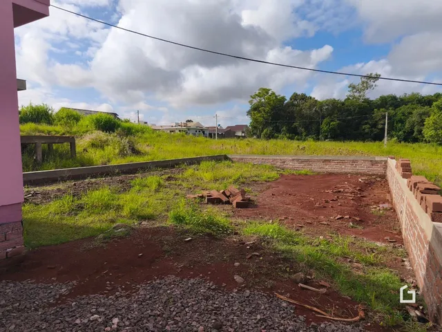 Vista externa de um terreno com muro de tijolos e vegetação.
