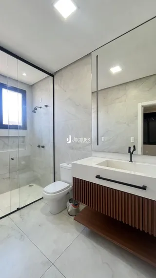 Banheiro moderno com revestimento em mármore branco e box de vidro.