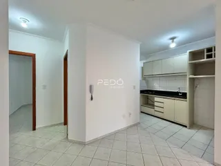 Interior de uma sala com cozinha e parede divisória branca.