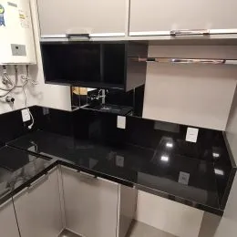 Foto de uma cozinha com armários escuros e bancadas pretas.