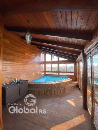 Interior de uma área com vista para uma piscina externa de madeira.