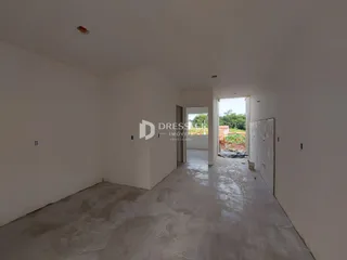 Interior de um espaço amplo com paredes brancas e piso de concreto.