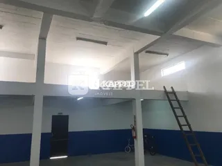Vista interna de um espaço com estrutura de concreto aparente e paredes azuis.
