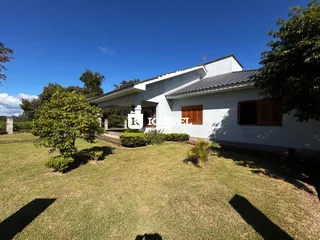 Fachada de uma casa branca com jardim gramado sob um céu azul.