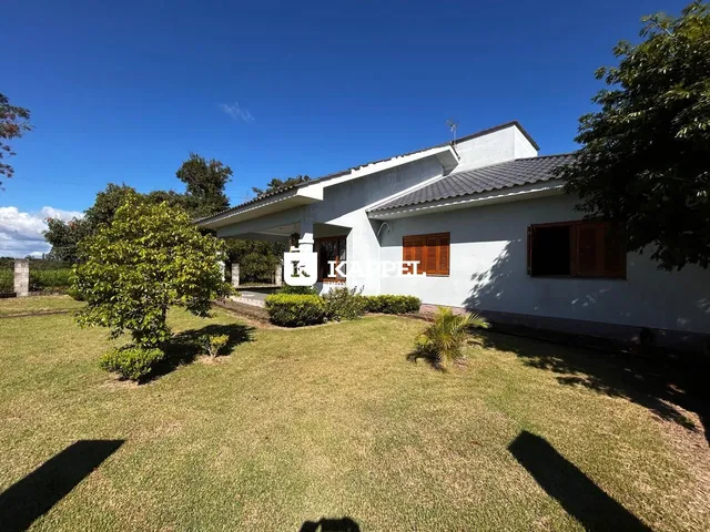 Fachada de uma casa branca com jardim gramado sob um céu azul.