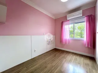 Quarto com paredes rosa e piso de madeira clara.