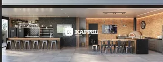 Vista interna de uma cozinha moderna com armários escuros e iluminação quente.