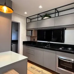 Cozinha moderna com armários escuros e bancada preta.