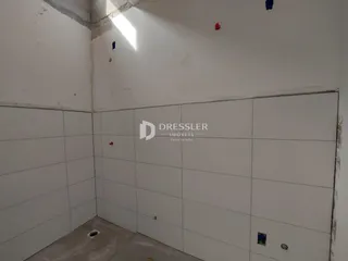 Foto do interior de um ambiente com paredes brancas e piso de cerâmica.