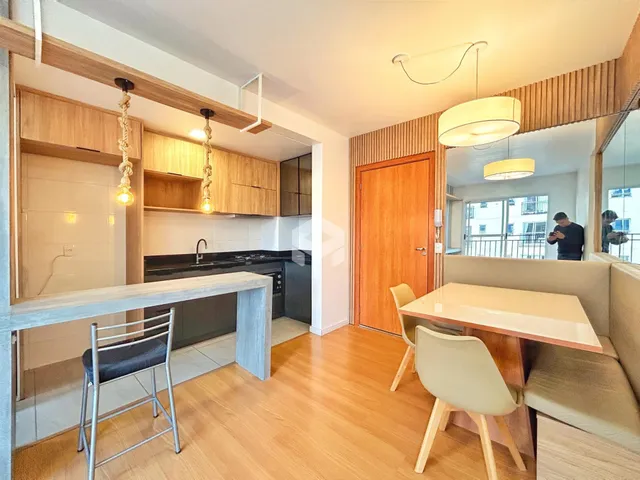 Ambiente de sala de estar com cozinha integrada e piso de madeira.