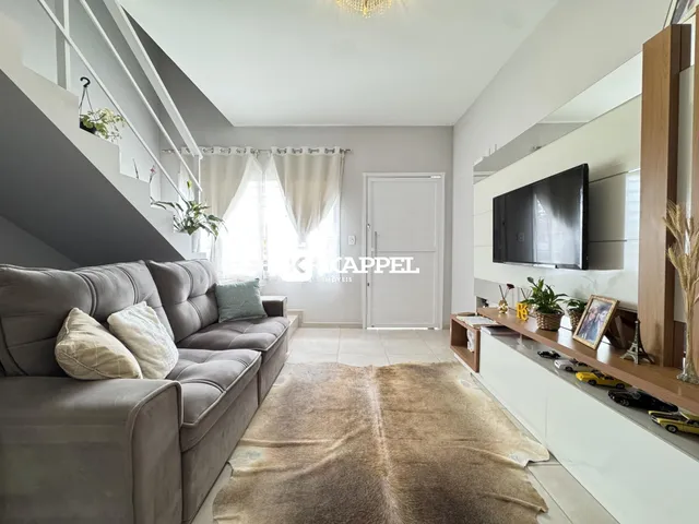 Sala de estar moderna com sofá grande e televisão montada na parede.