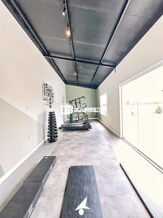 Foto de um corredor interno com piso de concreto e equipamento de ginástica.