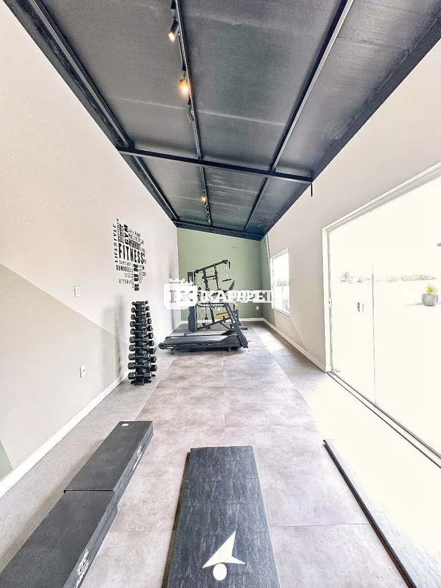 Foto de um corredor interno com piso de concreto e equipamento de ginástica.