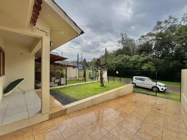Foto da fachada de uma casa com área externa e quintal cercado.