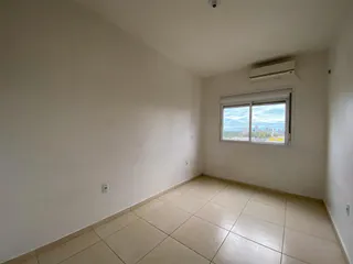 Foto interna de um cômodo com piso de cerâmica e janela com vista para a paisagem urbana.
