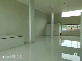 Interior de um espaço amplo com paredes brancas e piso claro.