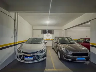 Vista de um corredor interno com dois carros estacionados.