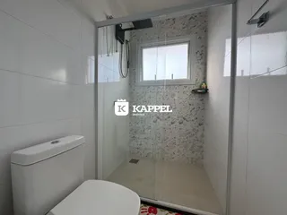 Banheiro com box de vidro e revestimento de azulejos brancos.